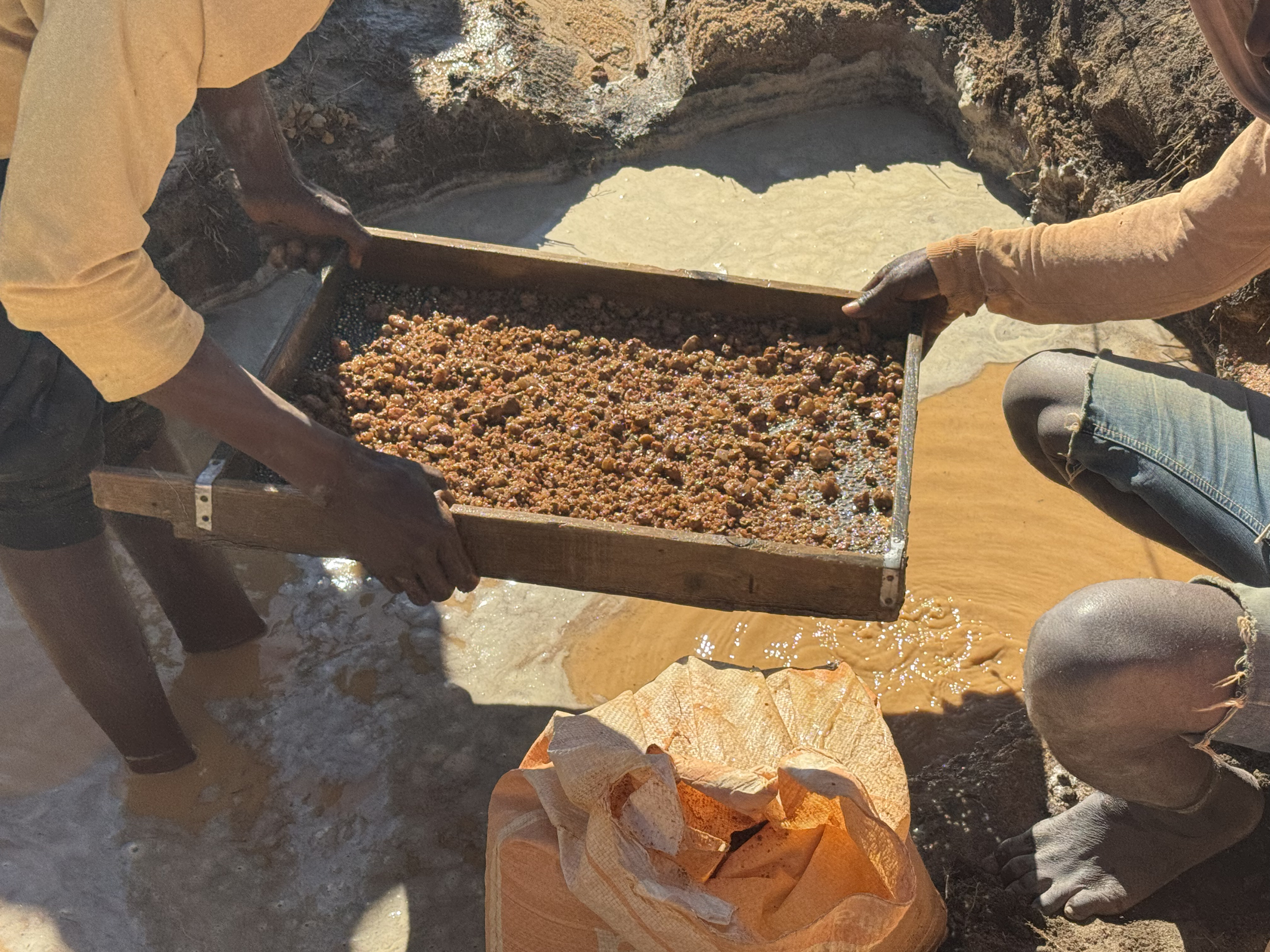 How We Travel the World to Source Our Crystals – Madagascar 2026 12 Miners sifting soil through a wooden frame searching for gemstones in Madagascar